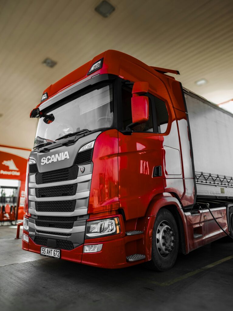 pexels photo 18942492 18942492 Bright red Scania truck parked at a fuel station with modern design and clean lines.
