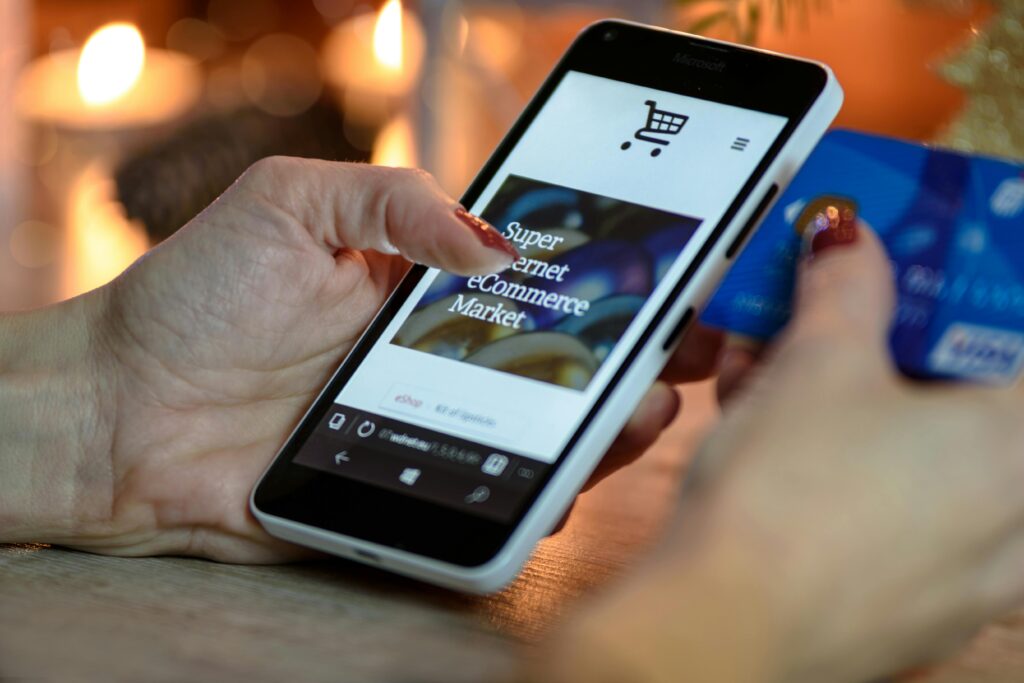 pexels photo 230544 230544 Woman using smartphone for online shopping with credit card in hand, festive background lighting.